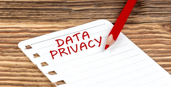 Word DATA PRIVACY on paper with ped pencil on wooden background