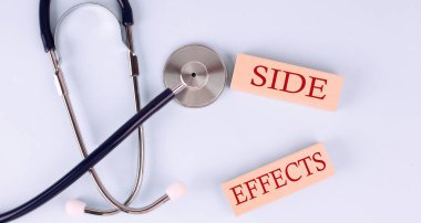 On a blue background, a stethoscope and wooden block with the word SIDE EFFETS .Medical