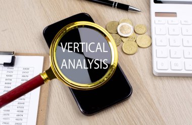 VERTICAL ANALYSIS text on magnifier with smartphone, calculator and coins