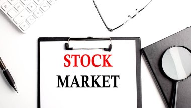 STOCK MARKET text written on a paper clipboard with office tools