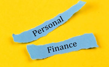 PERSONAL FINANCE text on blue pieces of paper on yellow background, business concept
