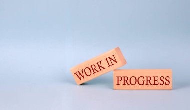 WORKS IN PROGRESS text on wooden block, blue background clipart