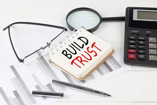 stock image BUILD TRUST text on a notebook with calculator on diagram background