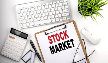 İş kavramı. Kağıt pano, kalem, gözlük, klavye ve hesap makinesi ile beyaz arkaplan üzerinde STOCK MARKET metni.