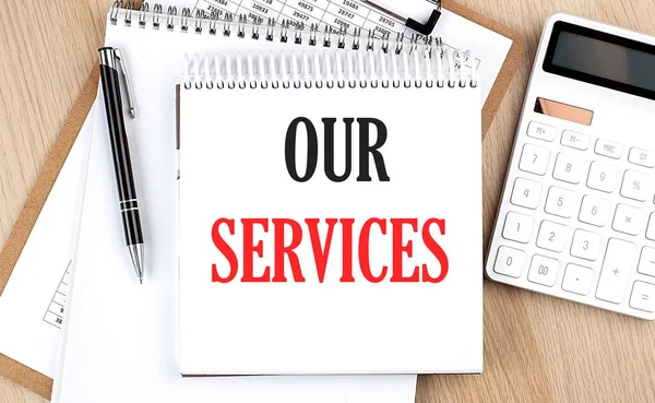 stock image OUR SERVICES is written in white notepad near a calculator, clipboard and pen. Business