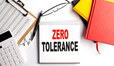 ZERO TOLERANCE text on notebook with clipboard and calculator on a white background