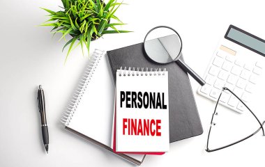 Text PERSONAL FINANCE on a notebook with office tools on white background
