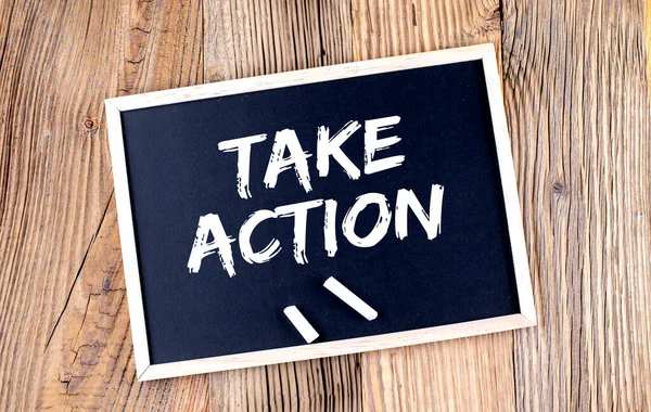 TAKE ACTION text on chalkboard on the wooden background