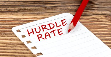 Word HURDLE RATE on paper with ped pencil on wooden background