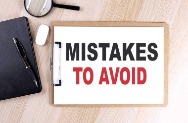 MISTAKES TO AVOID text on a clipboard on wooden background