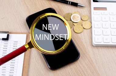 NEW MINDSET text on magnifier with smartphone, calculator and coins
