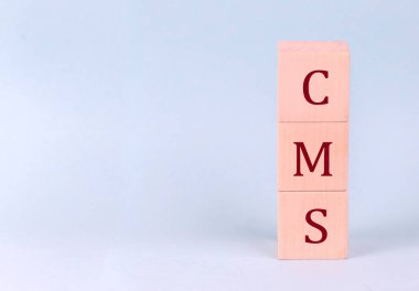 CMS on wooden cubes on blue background