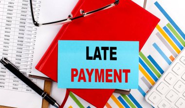 LATE PAYMENT text on a sticky on red notebook on chart background