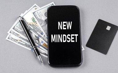 Dolar ve kalemle akıllı telefondan kredi kartı ve NEW Mindset mesajı. İş konsepti