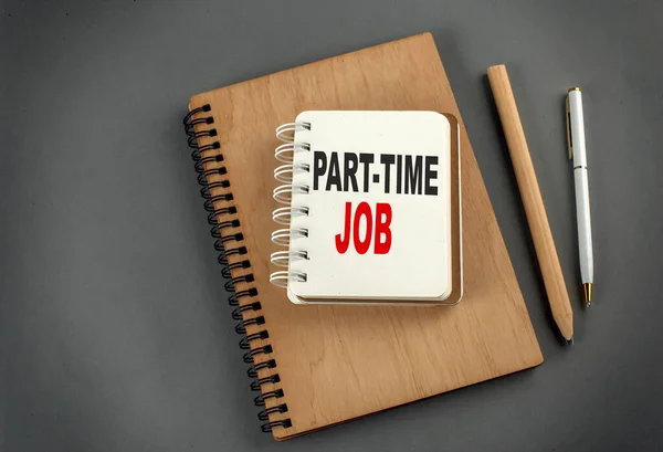 PART-TIME JOB text on a notebook with pen and pencil on grey background