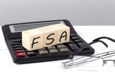 FSA kavramı, beyaz arkaplanda hesap makinesinde tahta küplerde