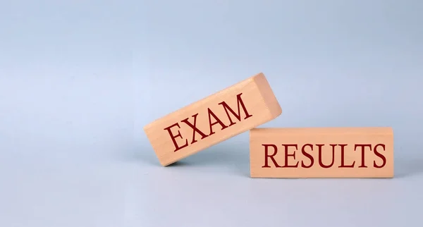 EXAM RESULTS text on wooden block, blue background