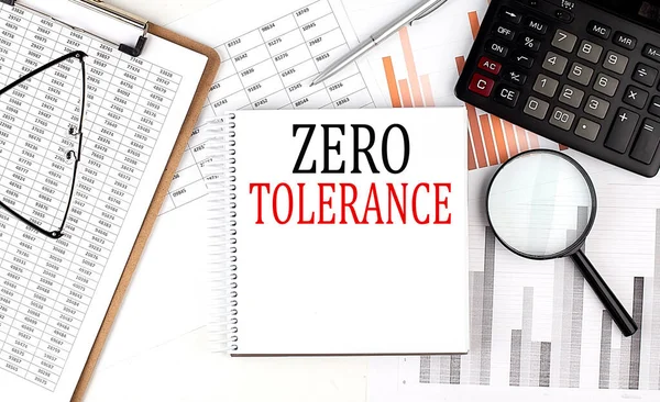 Not defterinde pano ve grafik arkaplanda hesap makinesi olan Sıfır TOLERANCE metni