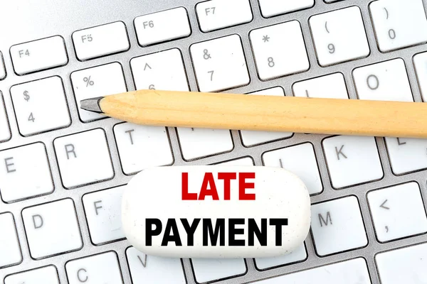 LATE PAYMENT text on a eraser with pencil on keyboard