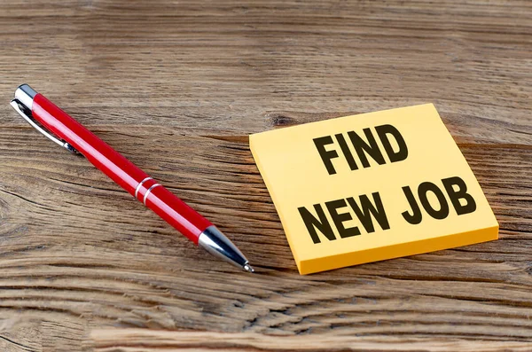 FIND NEW JOB text on a sticky with pen on the wooden background