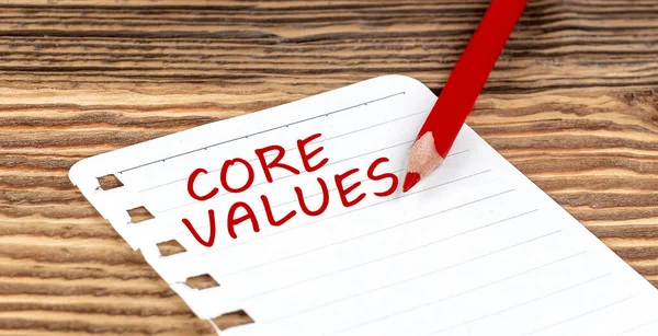 Word CORE VALUES on paper with ped pencil on wooden background