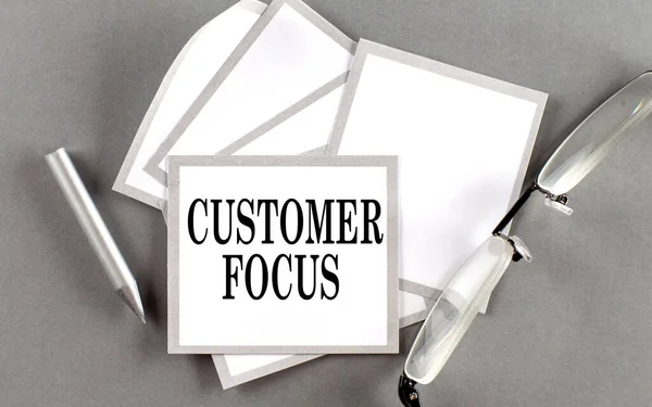 CUSTOMER FOCUS text written on sticky with pencil and glasses