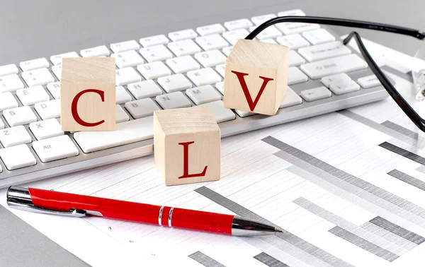 stock image CLV written on a wooden cube on keyboard with chart on grey background