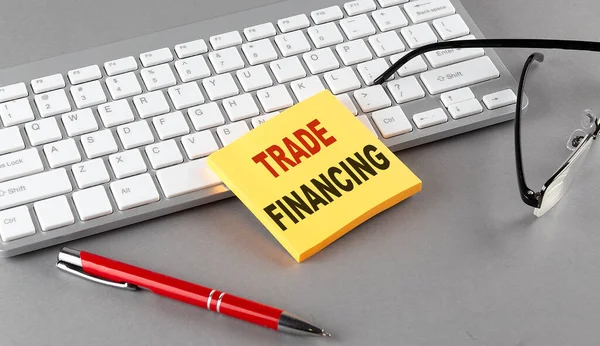 貿易金融キーボードで粘着性のあるテキスト グレーの背景にペングラス — ストック写真
