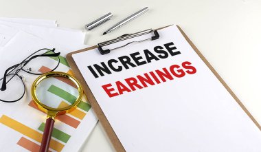 Beyaz arkaplan ve iş konsepti grafikli bir pano üzerinde INCREASE EARNINGS metni