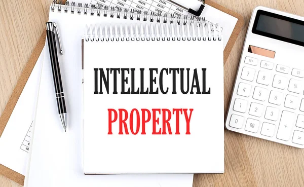 INTELLECTUAL PROPERTY is written in white notepad near calculator, clipboard and pen. Business concept