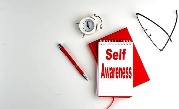 SELF AWARENESS text on a notebook , red pen and notebook, business concept, white background