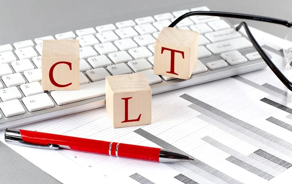 Stock image CLT written on wooden cube on the keyboard with chart on grey background