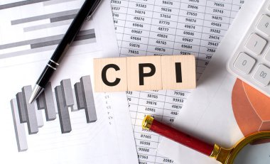 Grafik arkaplanındaki tahta blokta kalem ve büyüteçle CPI metni
