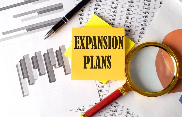 stock image EXPANSION PLANS text on sticky on the graph background with pen and magnifier