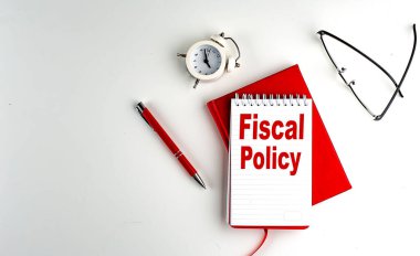 Not defterindeki FISCAL POLICY metni, kırmızı kalem ve defter, iş kavramı, beyaz arkaplan