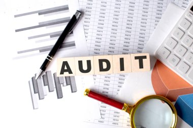 Grafik arkaplanındaki tahta blokta kalem ve büyüteçle AUDIT metni