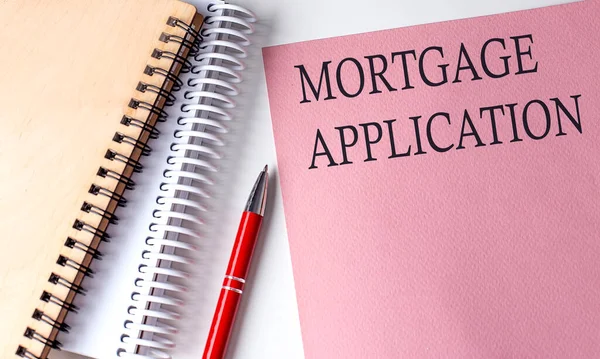 MORTGAGE APPLICATION word on pink paper with office tools on white background