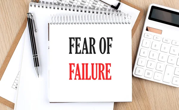 FEAR OF FAILURE is written in white notepad near calculator, clipboard and pen. Business concept