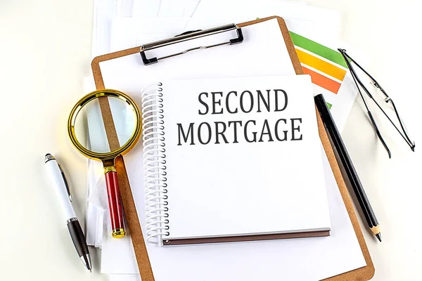 Stock image SECOND MORTGAGE text on a notebook with clipboard on white background