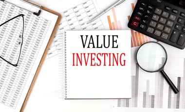 Not defterinde pano ve çizelge arka planında hesap makinesi olan VALUE INVESTING metni