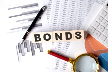 Grafik arkaplanındaki tahta bir blokta kalem ve büyüteçle BONDS metni