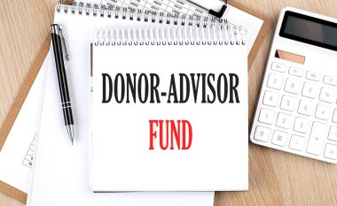 DONOR ADVISOR FUND hesap makinesi, pano ve kalemin yanında beyaz not defterine yazılmıştır. İş konsepti