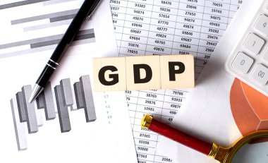Grafik arkaplanındaki tahta blok üzerinde kalem ve büyüteçle GSYİH metni