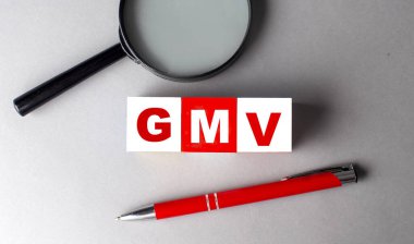 Kalem ve büyüteçle tahta küplere GMV kelimesi