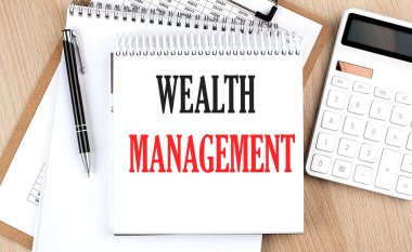 WEALTH MANAGEMENT bir hesap makinesi, dosya ve kalem yanında beyaz not defterine yazılmıştır. İş dünyası
