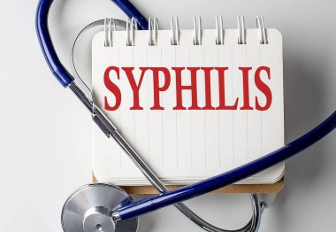 Arka planda tıbbi ekipman bulunan bir defterde SYPHILIS sözcüğü