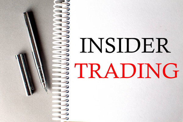 INSIDER TRADING text on notebook with pen on grey background
