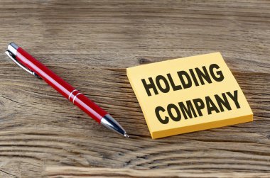 Ahşap arka planda kalemle yapışkan bir şeyin üzerine kurulmuş bir şirket metni