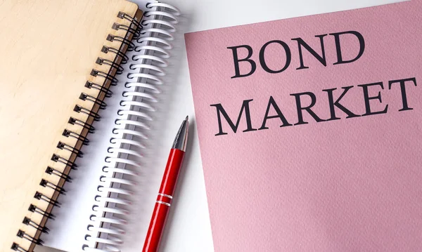 stock image BOND MARKET word on pink paper with office tools on white background