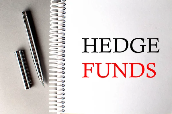 HEDGE FUNDS text on notebook with pen on grey background